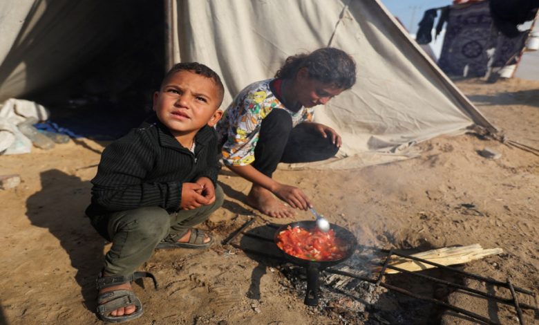 طفلان نازحان يعدان الطعام أمام خيمتهما في رفح. (رويترز)